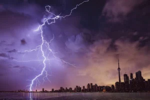 A striking lightning bolt illuminates the Toronto skyline against a dramatic stormy sky.