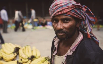 Portrait of a vendor selling bananas at an urban market, displaying cultural attire.