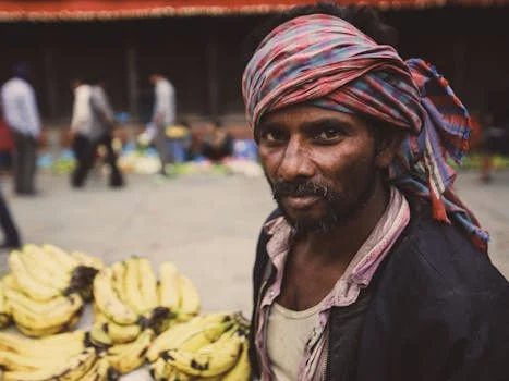 Portrait of a vendor selling bananas at an urban market, displaying cultural attire.