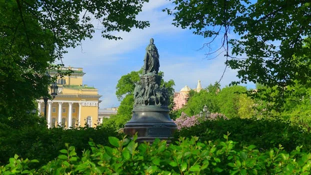 The statue of Catherine the Great surrounded by lush greenery in Saint Petersburg, Russia.