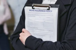 Close-up of a person holding a home insurance policy on a clipboard, captured indoors.