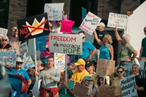 A diverse group of protesters holds signs advocating for freedom and democracy at a daytime rally.