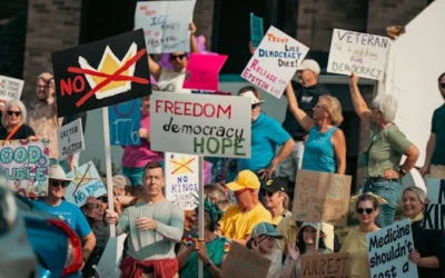 A diverse group of protesters holds signs advocating for freedom and democracy at a daytime rally.