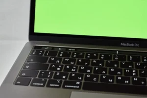 Russian keyboard MacBook Pro with a green screen. Modern electronic device.